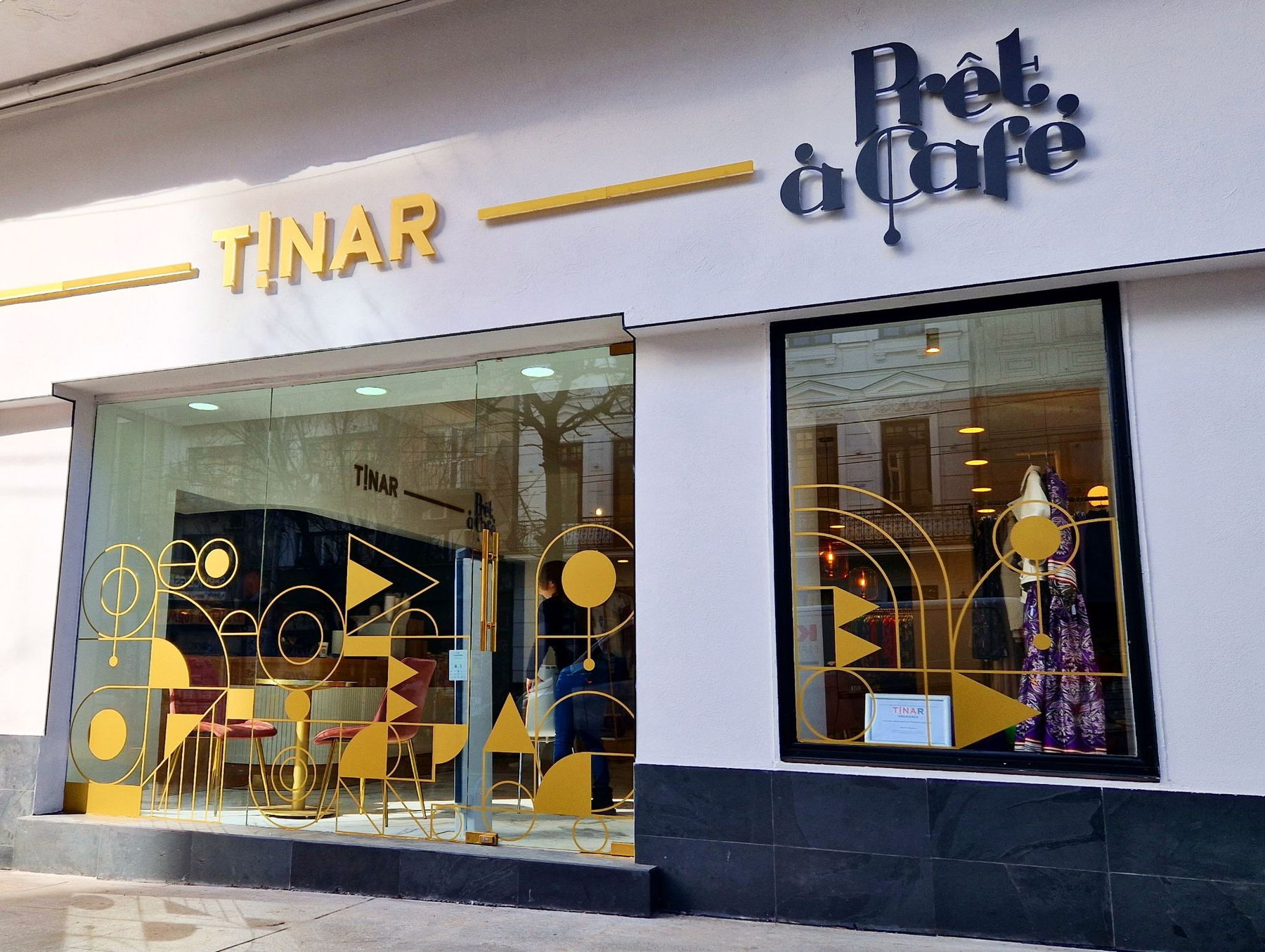 Vitrina Prêt à Café și TINAR, cu decorațiuni geometrice aurii, pe un bulevard din București